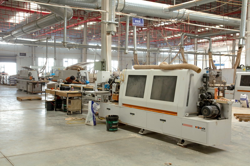 Industrial edge banding machine applying moisture-resistant seals to engineered wood panels.